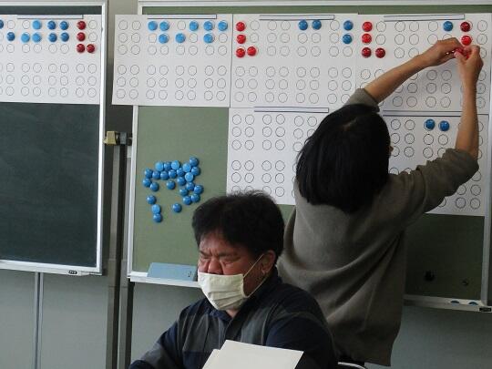 講師が黒板に点字を書き説明する様子