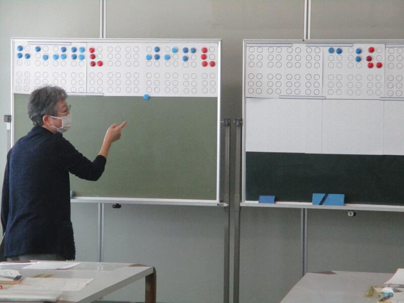 講師が黒板に点字を書き説明する様子