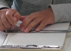 点字器と点筆を使って点字を書く様子